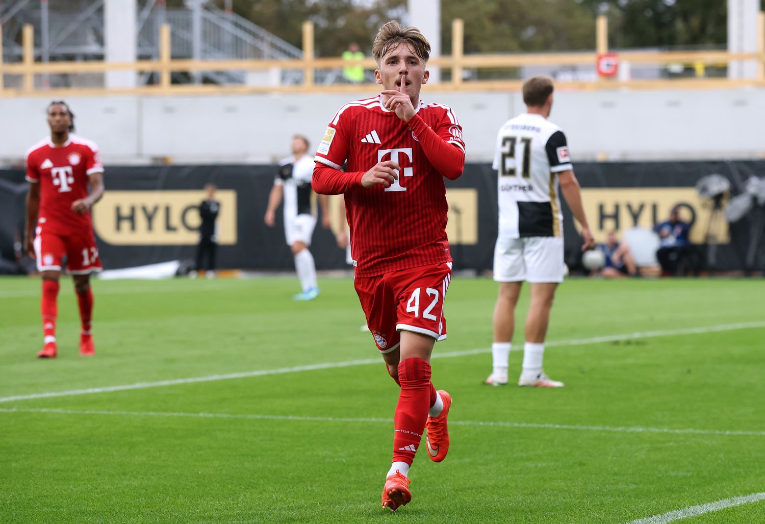 Der FC Bayern ist mit einem blauen Auge davongekommen. Vier Tage nach der 5:0-Gala in der Champions League gegen Bodø/Glimt mussten die Münchner beim Bundesliga-Aufsteiger SV Elversberg deutlich mehr investieren. Am Ende setzte sich die Mannschaft von Vincent Kompany knapp mit 2:1 durch.Zum Matchwinner avancierte einmal mehr Harry Kane. Der Engländer erzielte in der 73. Minute den entscheidenden Treffer und verhinderte damit den nächsten Punktverlust des Rekordmeisters nach dem 0:0 auf Schalke. Zuvor hatte Lennart Karl die Bayern in Führung gebracht, ehe ausgerechnet Ex-FCB-Talent Maurice Krattenmacher für Elversberg ausglich. Kompany nutzte die Partie, um einigen seiner Leistungsträger eine Verschnaufpause zu gönnen. Manuel Neuer, Joshua Kimmich, Luis Díaz und Jamal Musiala saßen zunächst auf der Bank. Zwischen den Pfosten begann Jonas Urbig. Die neu formierte Bayern-Elf hatte zwar viel Ballbesitz, traf aber auf einen Gegner, der sich keineswegs versteckte. Elversberg störte früh, ging mutig in die Zweikämpfe und stellte die Münchner damit immer wieder vor Probleme. ## Karl steht am richtigen Ort Trotz des couragierten Auftritts der Gastgeber erspielten sich die Bayern zunächst die besseren Möglichkeiten. Kane fand mit einem Abschluss keinen Weg zum Tor, Aleksandar Pavlovic zielte vorbei und auch Karl konnte seine erste Gelegenheit nicht nutzen. In der 27. Minute machte es der Youngster besser. Ausgangspunkt war eine starke Aktion von Ismael Saibari auf der linken Seite. Seine Hereingabe fand zunächst keinen Abnehmer, doch Karl reagierte am zweiten Pfosten am schnellsten und brachte den Favoriten mit 1:0 in Führung. Wer nun mit einer souveränen Vorstellung der Münchner gerechnet hatte, wurde enttäuscht. Elversberg blieb im Spiel und hätte kurz vor der Halbzeit beinahe zurückgeschlagen. Cole Campbell überwand Urbig, der vermeintliche Ausgleich wurde wegen einer knappen Abseitsstellung jedoch wieder einkassiert. Auch nach der Pause hielt der Aufsteiger an seinem mutigen Ansatz fest. Besonders ein Spieler mit Bayern-Vergangenheit sollte den Gästen schließlich wehtun. ## Krattenmacher schockt seinen Ex-Klub Zunächst hatte Kane das vermeintliche 2:0 erzielt, doch auch dieser Treffer zählte aufgrund einer Abseitsposition nicht. Statt einer komfortableren Führung stand es wenig später plötzlich 1:1. Der eingewechselte Maurice Krattenmacher fasste sich ein Herz und schlenzte den Ball sehenswert in den Winkel. Ausgerechnet der frühere Bayern-Spieler sorgte damit dafür, dass die Partie wieder völlig offen war. Kompany reagierte und erhöhte mit seinen Wechseln das Risiko. Kimmich, Díaz und Alphonso Davies kamen in die Partie, woraufhin der Druck der Gäste spürbar zunahm. Díaz verpasste nach einer Olise-Vorlage mit der Hacke die erneute Führung. Kurz darauf scheiterte Olise mit einem gefühlvollen Chip an der Latte. Dann schlug Kane zu. Stanisic eroberte in der 73. Minute stark den Ball und leitete damit den schnellen Gegenangriff ein. Der englische Torjäger wurde bedient, verschaffte sich den nötigen Raum und ließ sich die Gelegenheit zum 2:1 nicht nehmen. ## Bayern bringt knappen Vorsprung über die Zeit Entschieden war die Begegnung damit allerdings noch nicht. Elversberg suchte weiter den Weg nach vorne und hielt die Bayern bis in die Schlussphase unter Spannung. Gleichzeitig verpassten die Münchner mehrfach die Gelegenheit, mit einem dritten Treffer frühzeitig für klare Verhältnisse zu sorgen. Erst in den letzten Minuten gelang es der Kompany-Elf, dem Spiel die nötige Ruhe zu geben. Die Bayern ließen den Ball durch die eigenen Reihen laufen und hielten Elversberg weitgehend vom eigenen Strafraum fern. Nach dem torlosen Remis auf Schalke kehrt der Rekordmeister damit in der Bundesliga auf die Siegerstraße zurück. Von der Leichtigkeit des Champions-League-Auftritts gegen Bodø/Glimt war dieses Mal allerdings wenig zu sehen. Elversberg verlangte dem Favoriten alles ab und schnupperte zwischenzeitlich an einer Überraschung. Am Ende verfügten die Bayern jedoch über den entscheidenden Unterschied im Sturmzentrum: Wenn es eng wird, ist auf Harry Kane weiterhin Verlass.